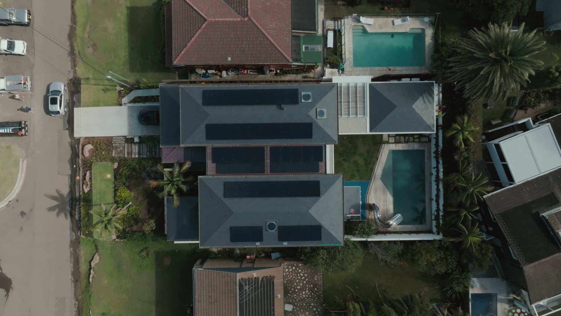 Top-down drone view of two homes with full black solar arrays