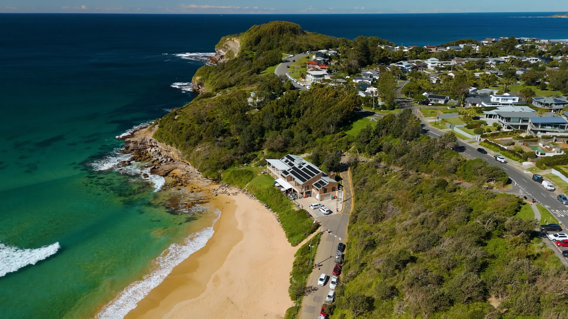 Aerial view of a coastal Sydney headland with solar panels on a beachfront home